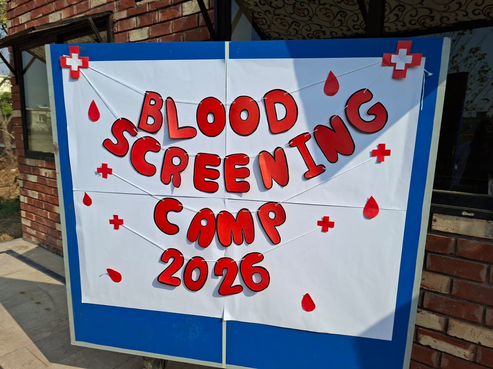 Hand-made banner reading Blood Screening Camp 2026 on the ISSA campus