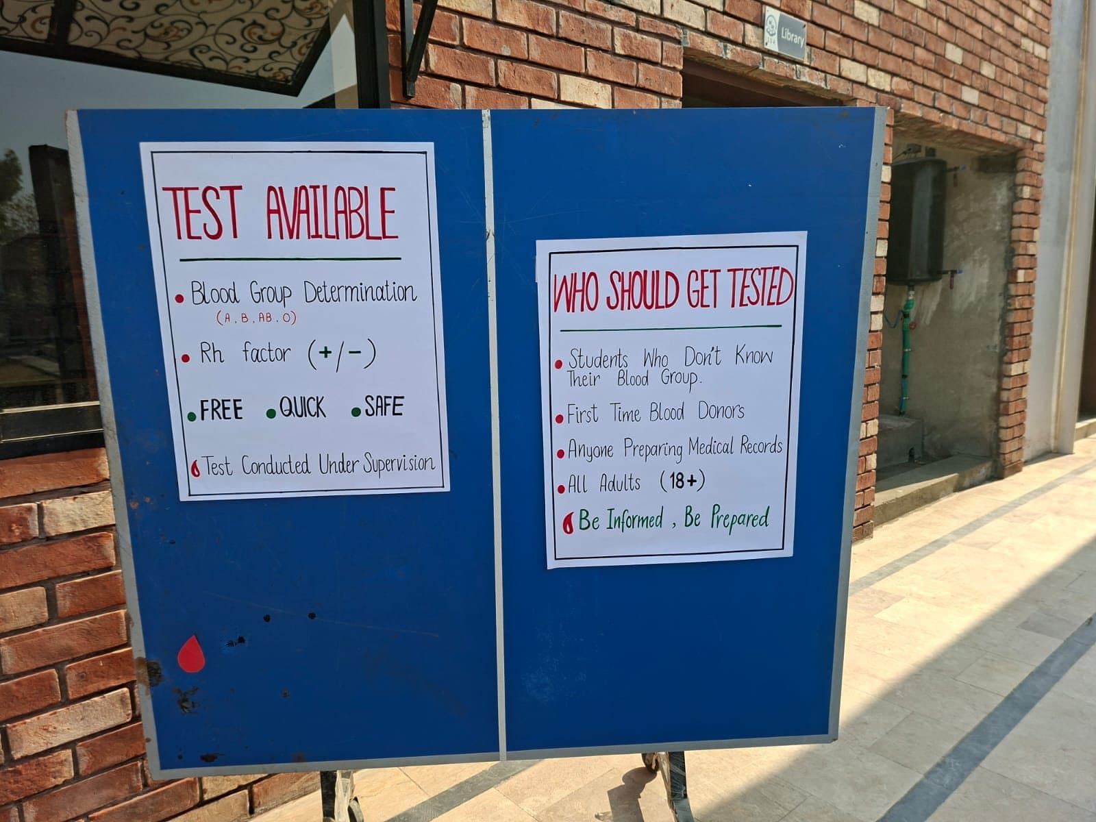 Notice board listing the free tests — blood group (A, B, AB, O) and Rh factor — and who should get tested