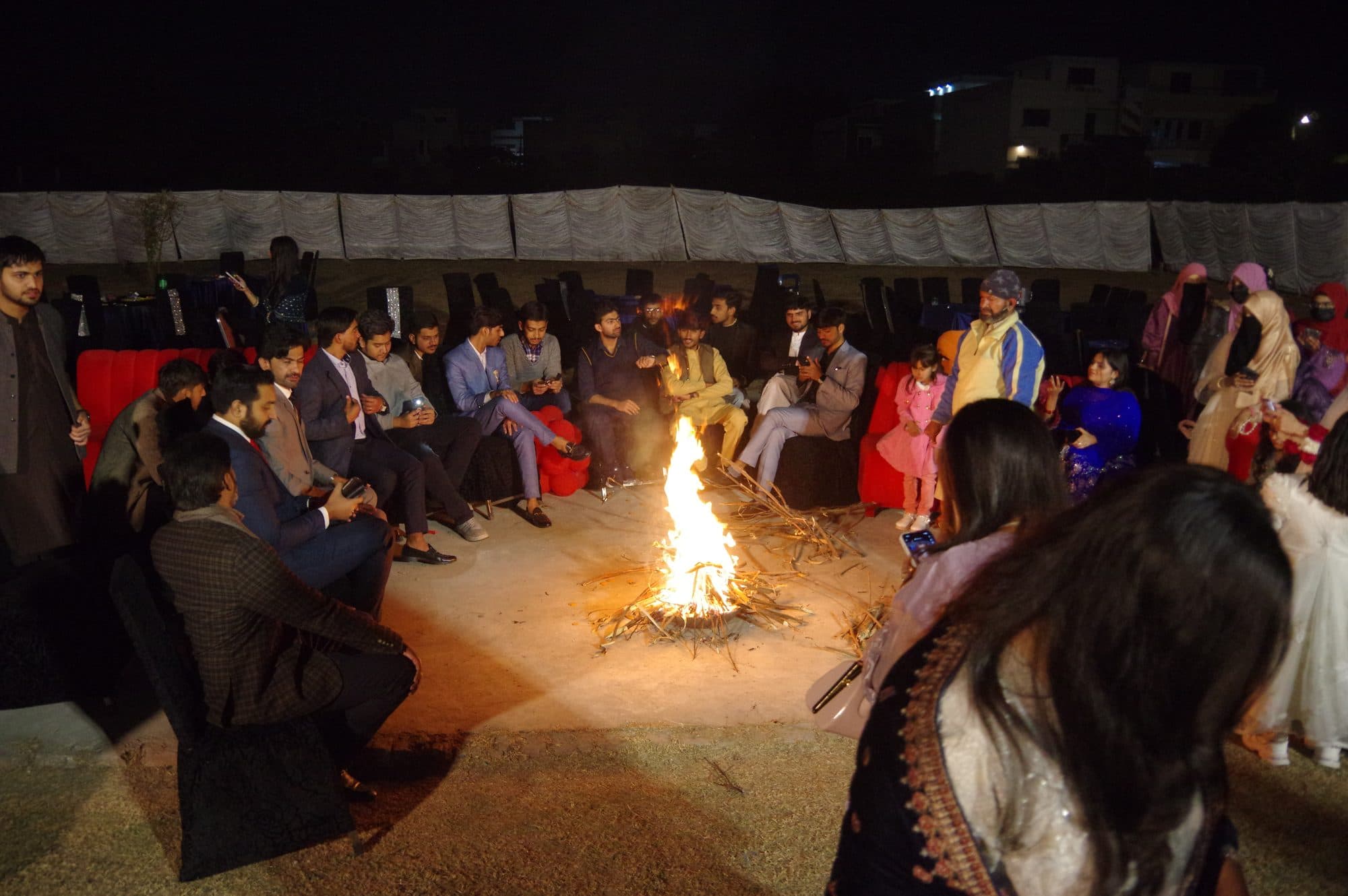 Students seated around a bonfire on the evening of the Freshers' Party