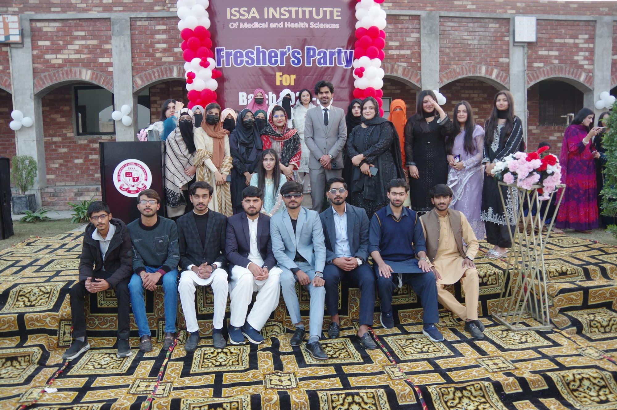 Students and faculty seated together for a group photograph at the Freshers' Party