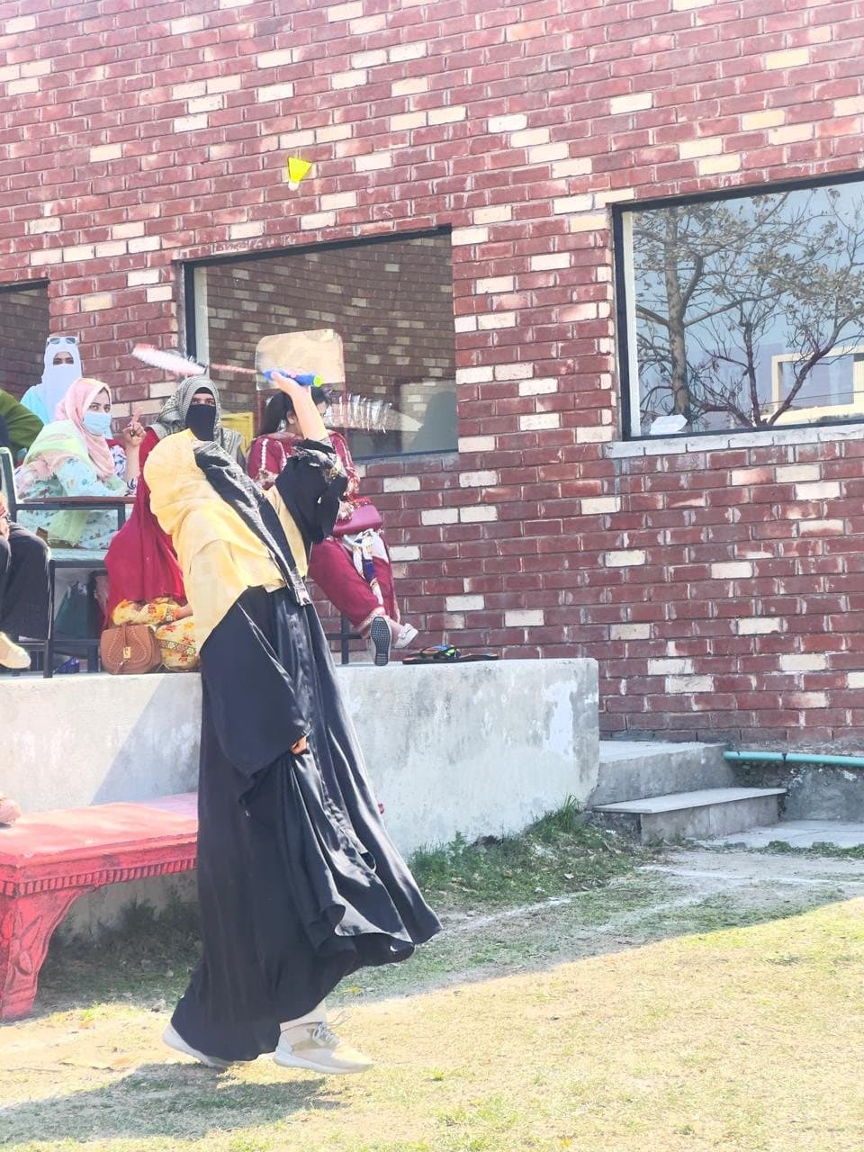 A student playing badminton beside the campus building during the Sports Gala