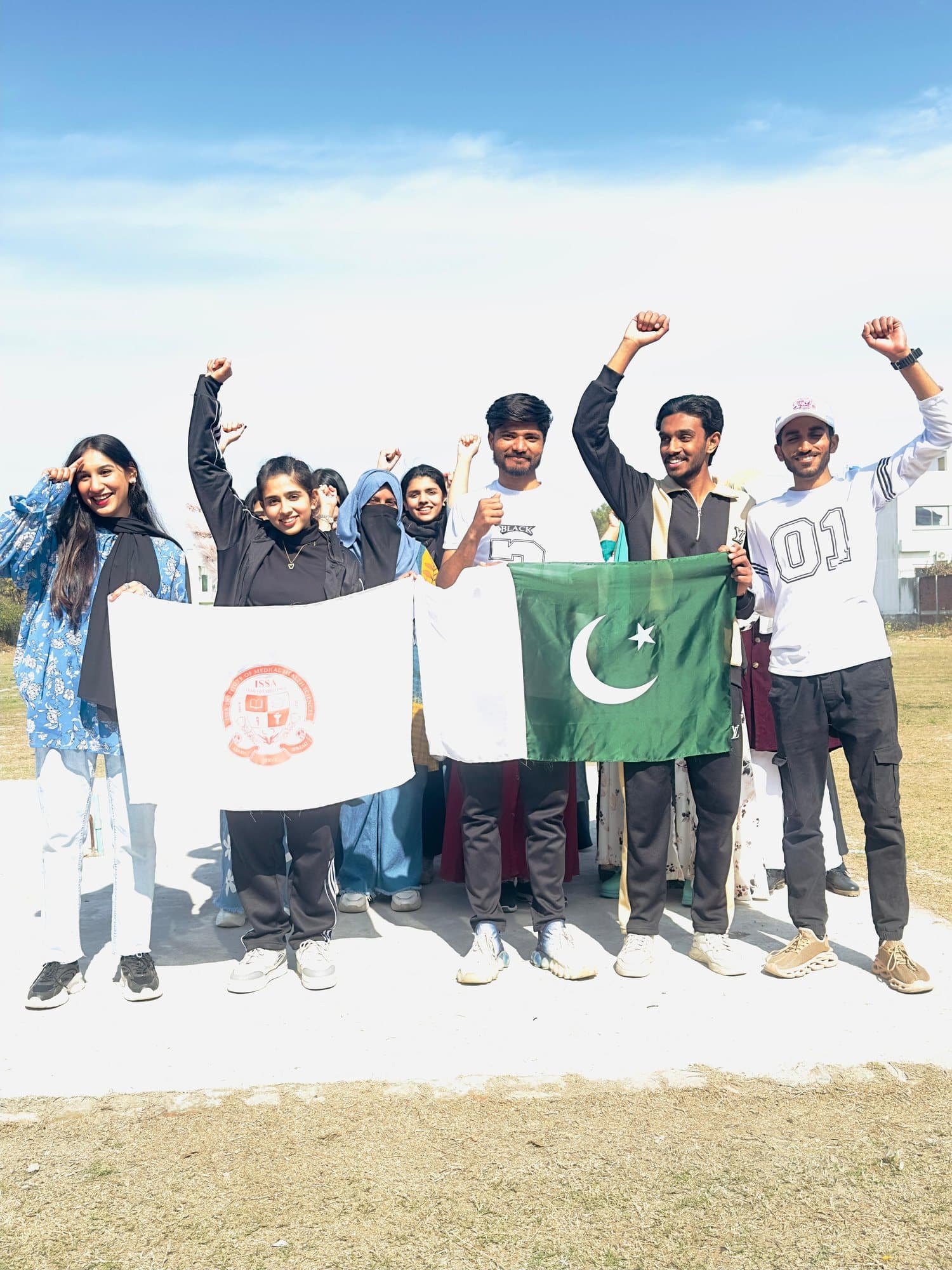 Students raising their fists with the ISSA and Pakistan flags at the Sports Gala