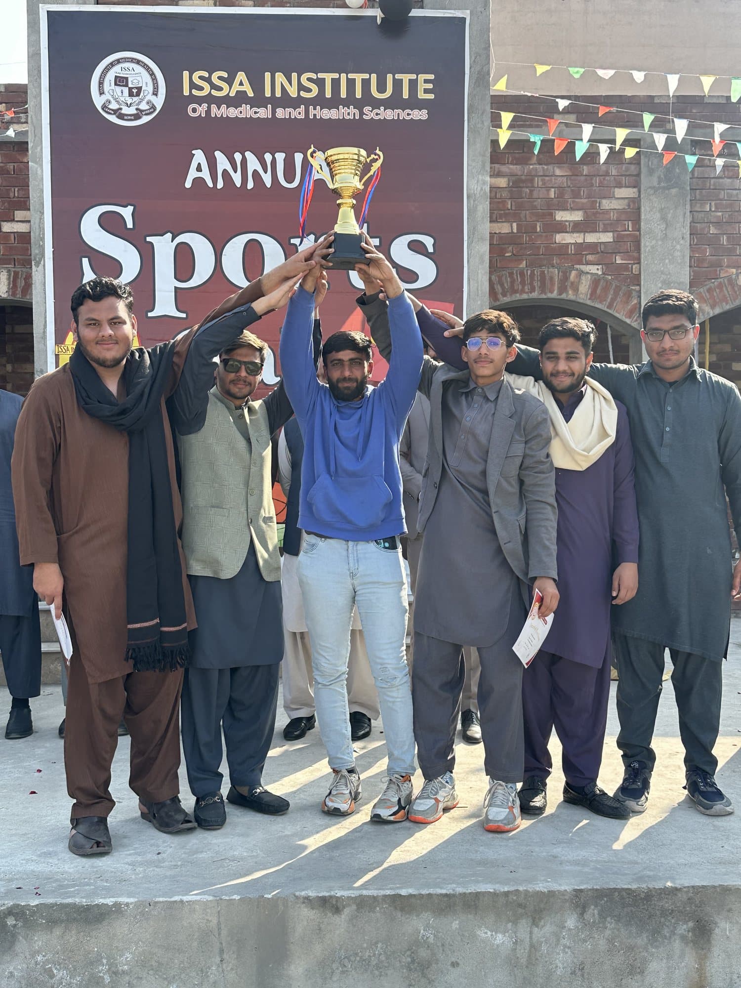 Students lifting a trophy in front of the Annual Sports Gala banner