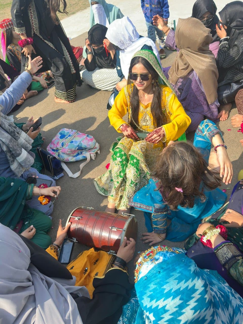 ISSA students in traditional Pakistani dress posing with a dhol on the campus ground on Culture Day